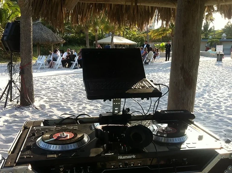 DJ controller set up under a tiki hut for a beachside event