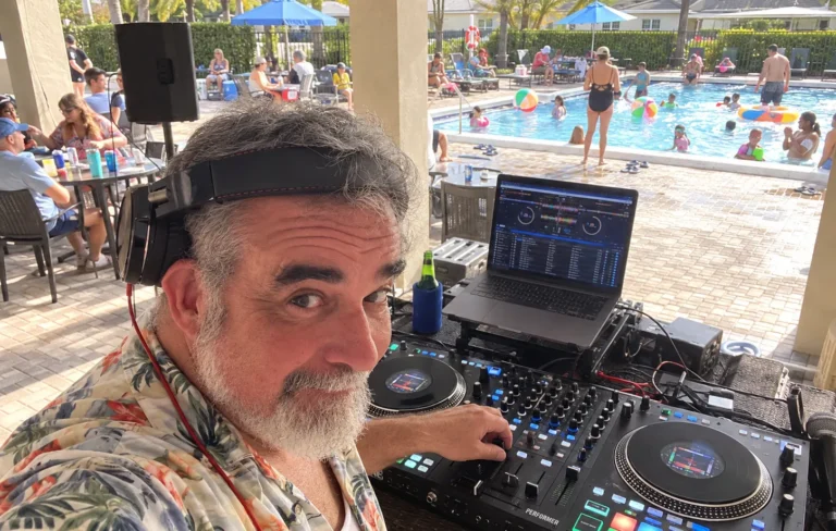 DJ 2RO in a tropical shirt at a Rane Performer controller during a community pool party
