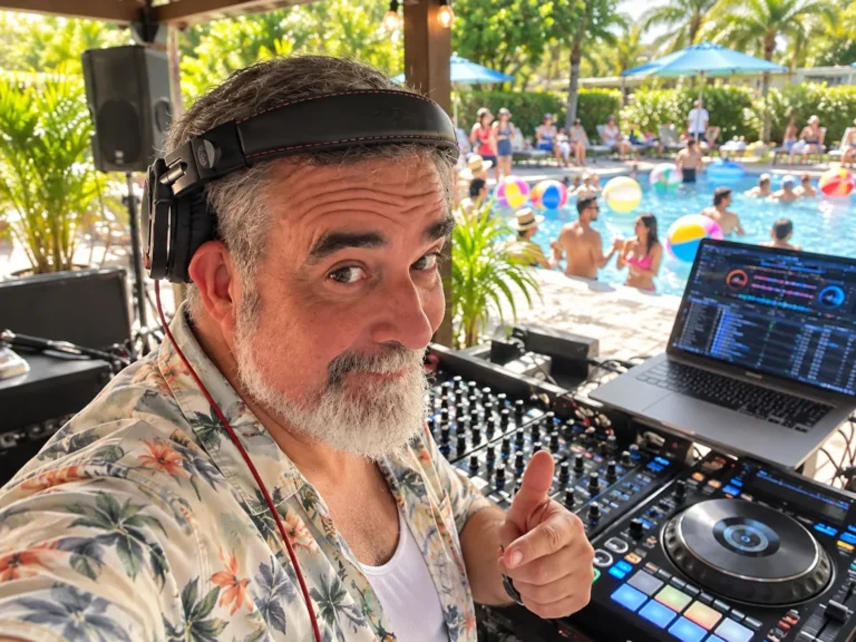 DJ 2RO giving a thumbs-up from the DJ booth at a poolside party