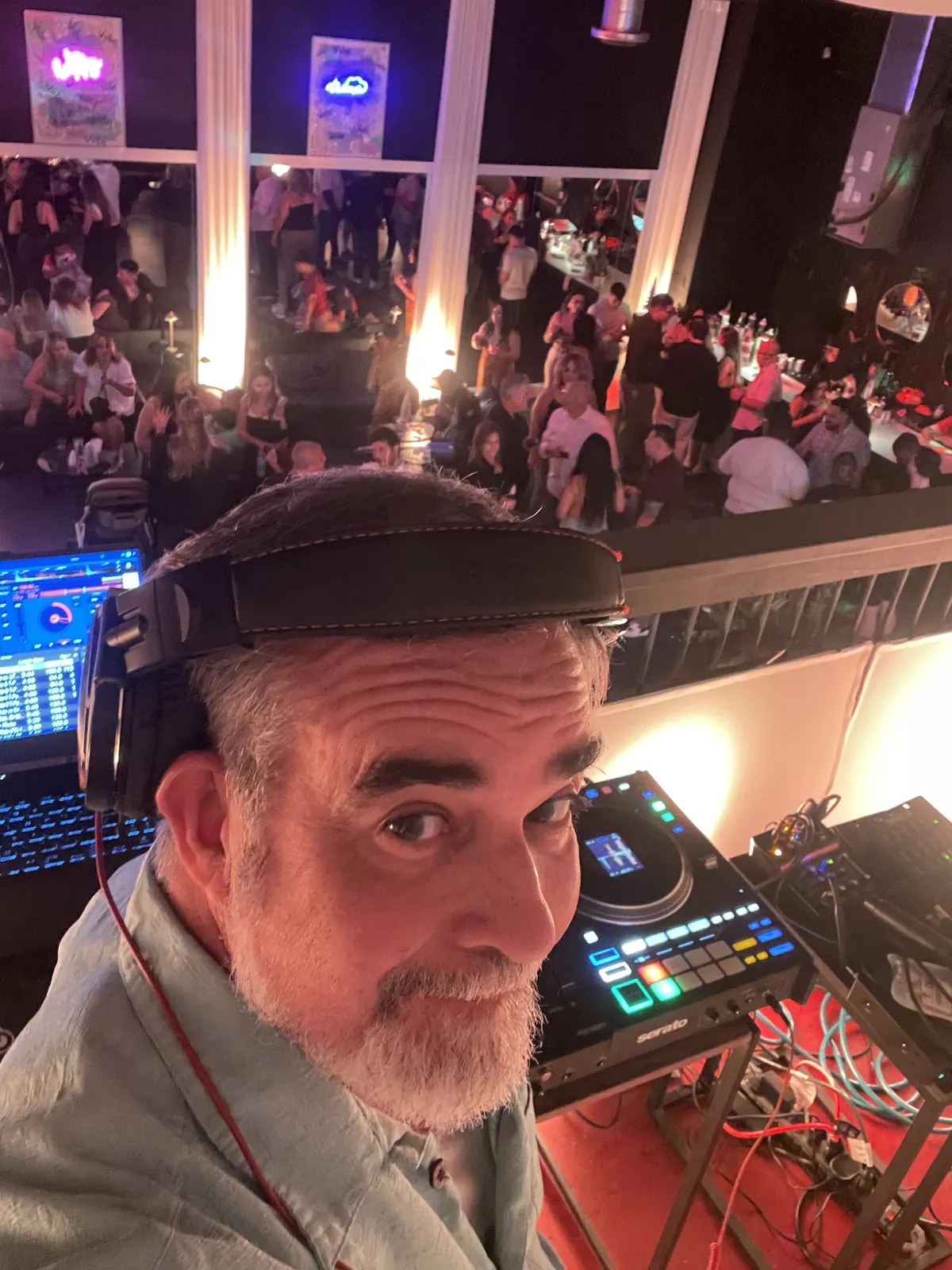 DJ 2RO (Arturo Morejon) in headphones at the decks above a packed nightclub crowd
